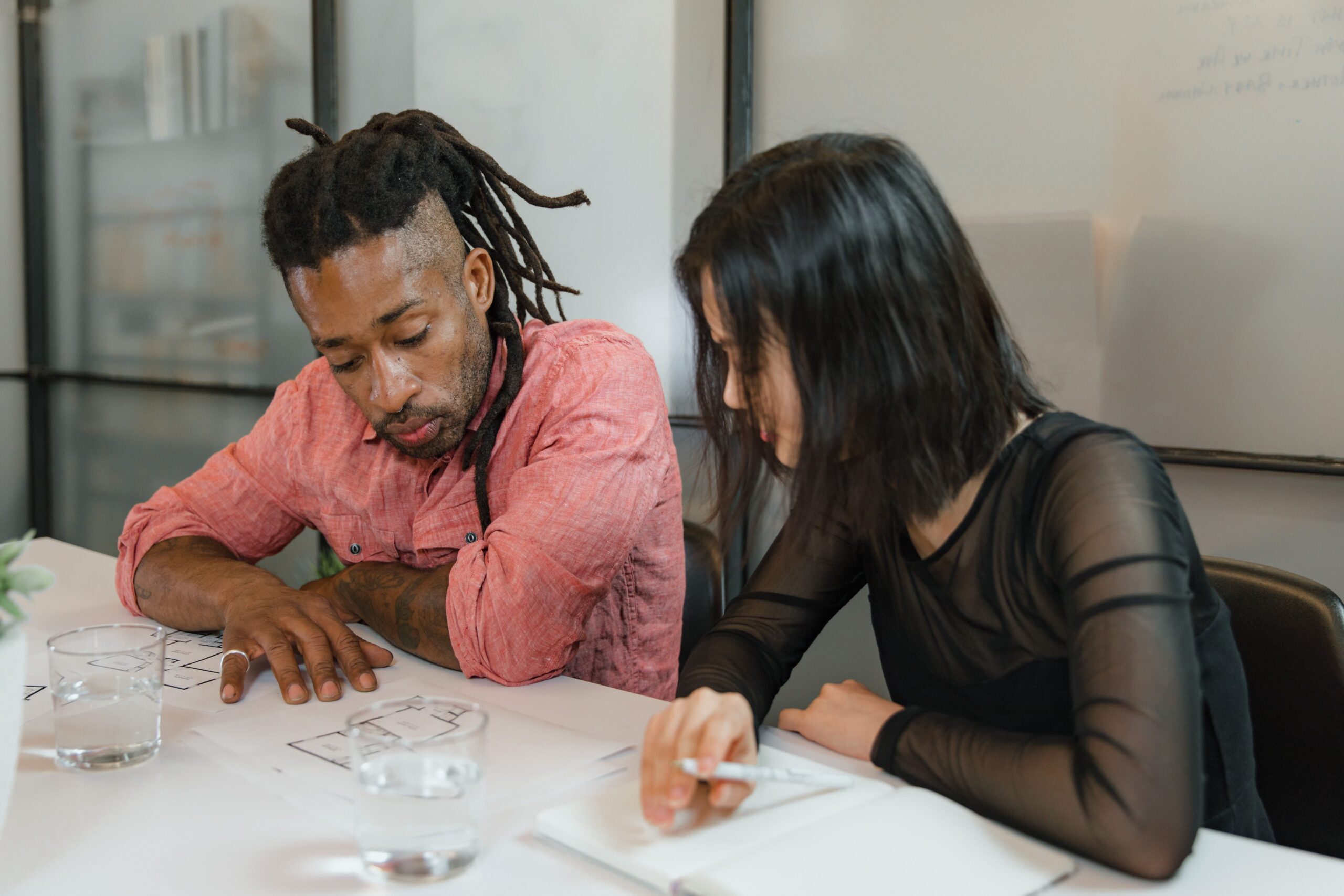 Two colleagues collaborate on design plans in a modern office setting. Focus on teamwork.